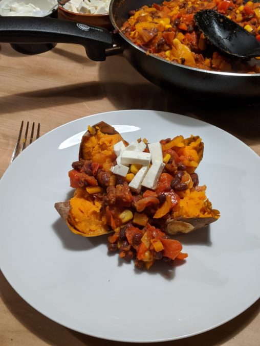 A picture of one of the completed dishes. A sweet potato topped with vegetable chilli and cheese