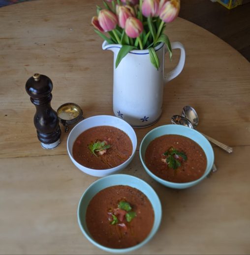 Three bowls of gazpacho soup on a dining table