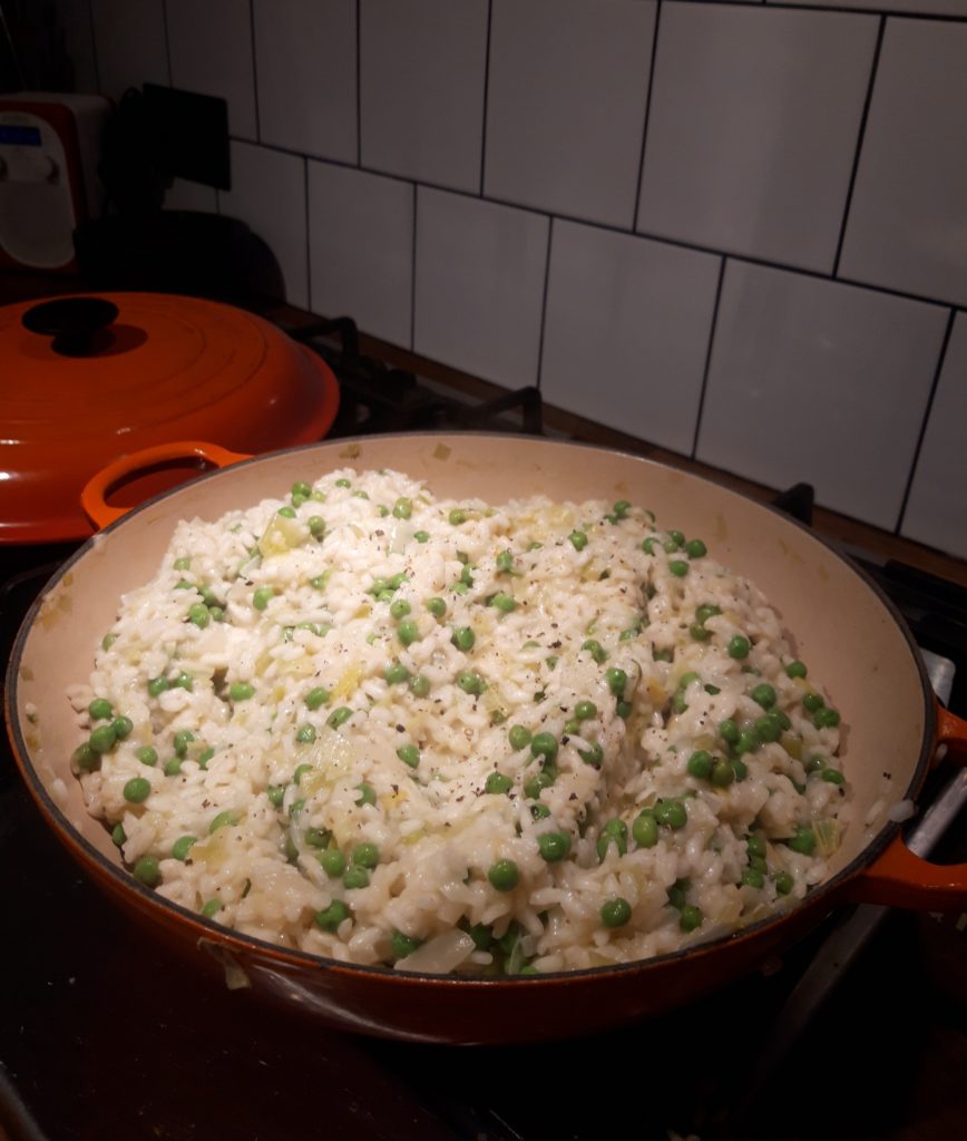 Image shows a large pan of risotto on the kitchen counter. this risotto uses summer vegetables.