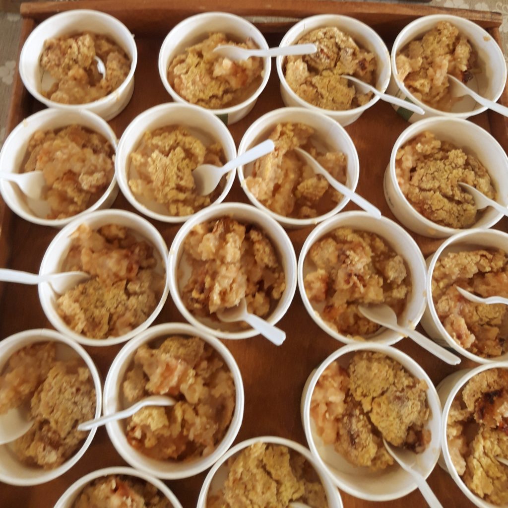 Image shows little round vegware pots with individual portions of apple crumble