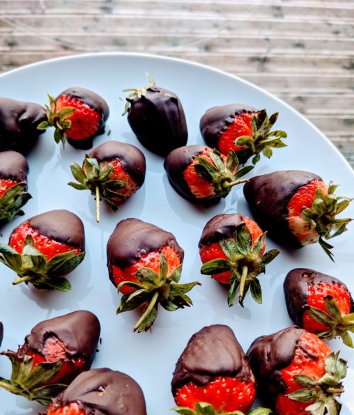 A white plate with chocolate dipped fresh strawberries.