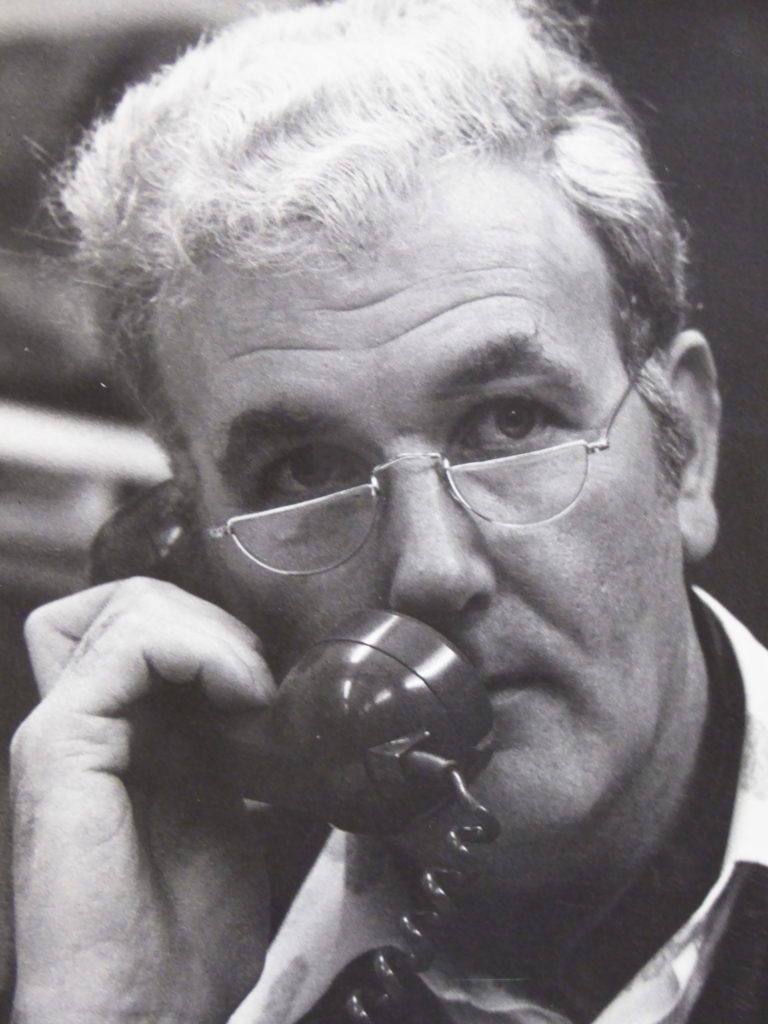 Black and white photograph showing Ross Eudall speaking into a telephone.