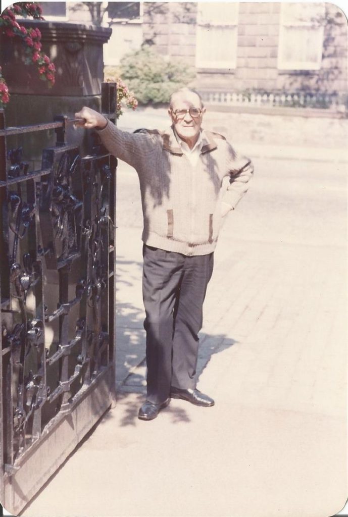 Photograph showing Harry Lonie standing next to the gates he made at the East entrance of RBGE in 1984.