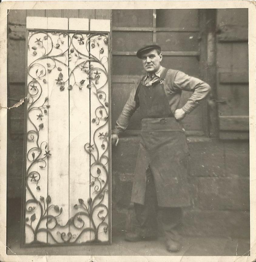 Black and white photograph showing Harry Lonie as a young man standing next to a gate he has made for an Edinburgh professor.