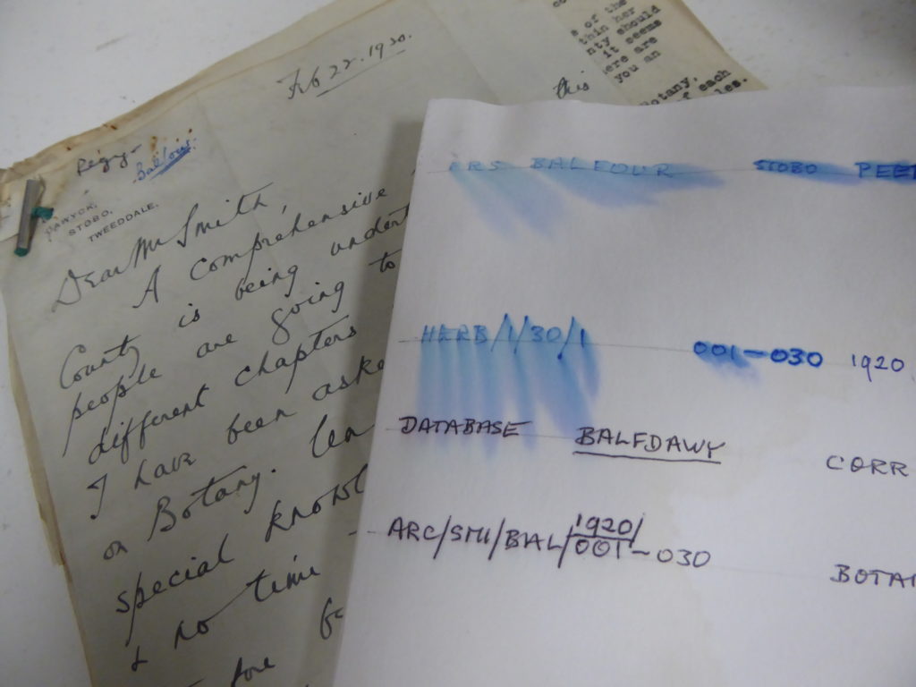 photograph showing a folder that has water stains and examples of blue ink running across the cover alongside letters that were inside the folder but are undamaged by the water.