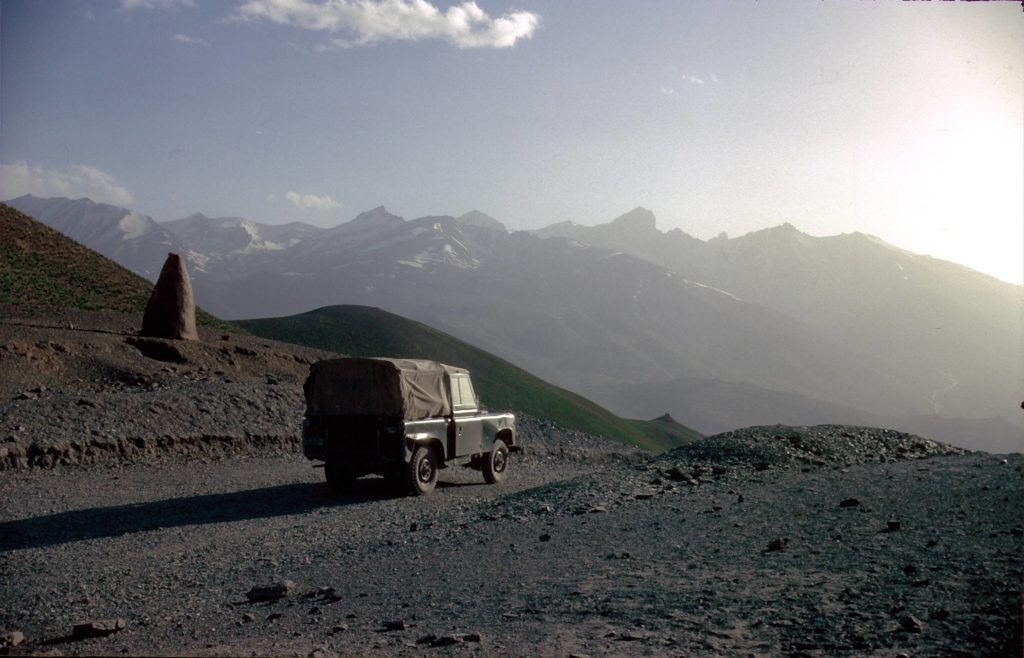 A Land Rover on a dirt road in a dry, mountain landscape